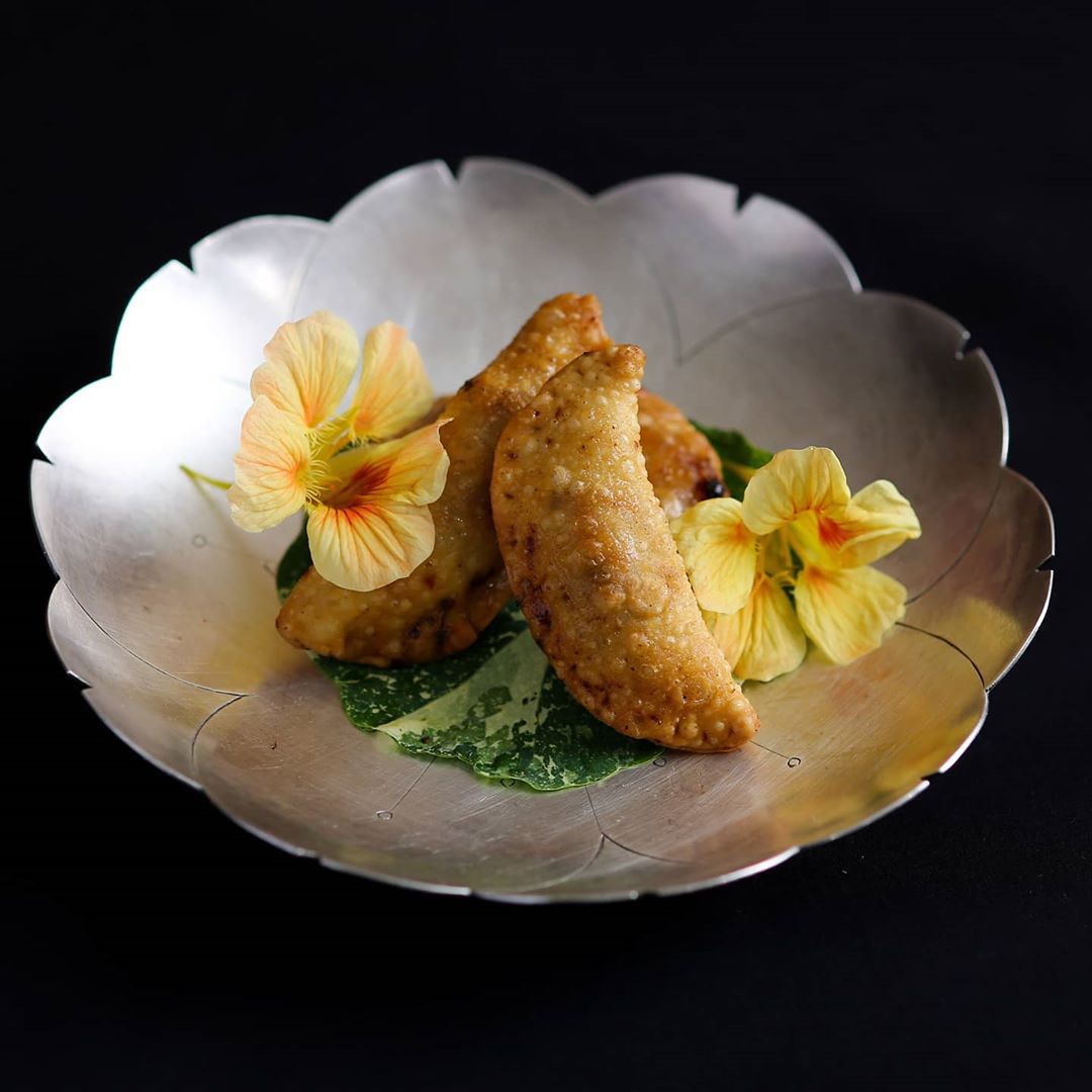 A beautifully presented dish of samosas and flowers.