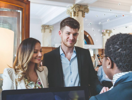 A couple smiling at the hotel receptionist