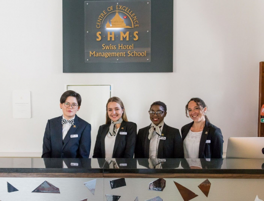 Four hotel receptionists smiling at the camera